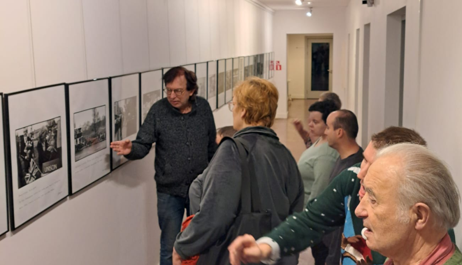 Ļaudis aplūko foto un gleznu izstādi